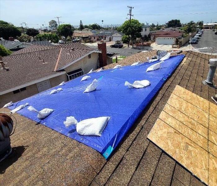 Hole on the roof covered up with a blue tarp and sandbags